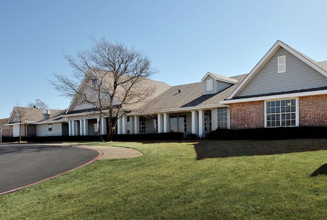 A suburban residential building with a well-maintained lawn and driveway on a clear day.