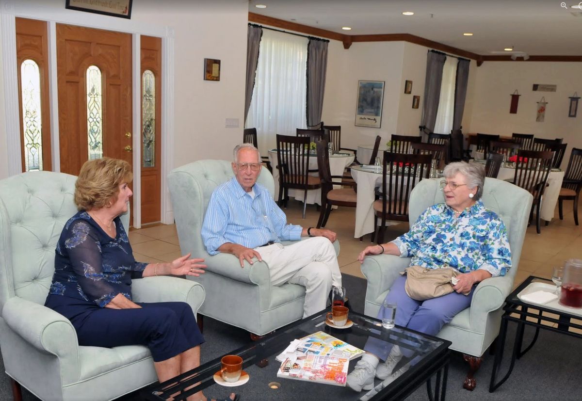 Three people having a conversation in a living room setting.
