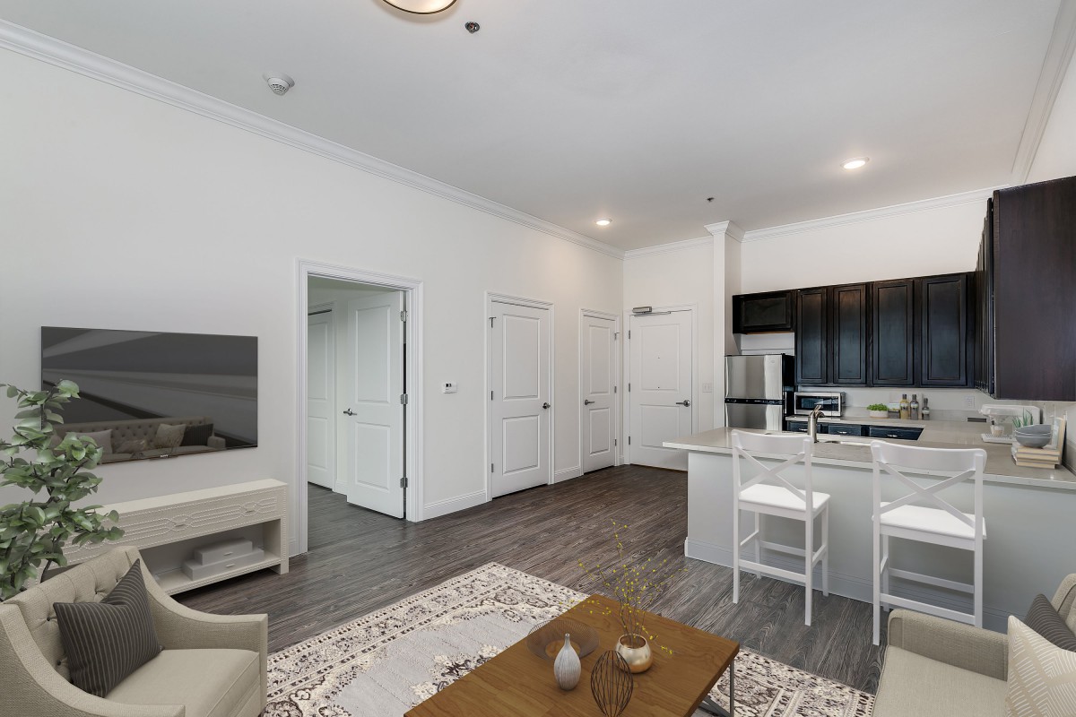 A modern living space featuring an open floor plan with a kitchen and living area, highlighted by minimalist decor and hardwood flooring.