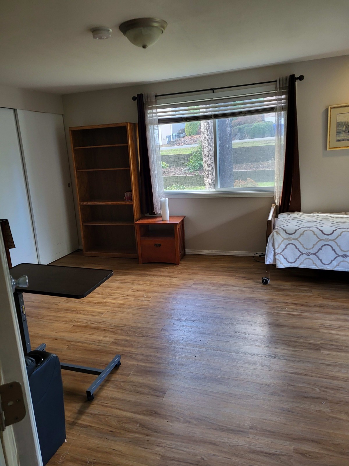 Spacious bedroom with wooden flooring, a bed, and large window.