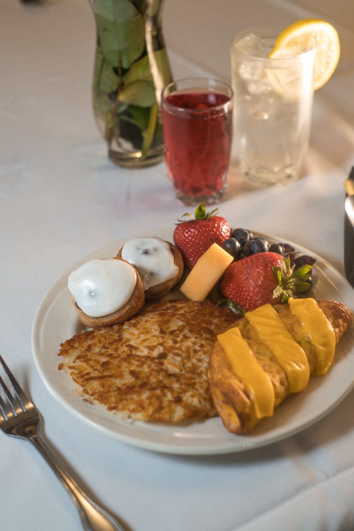 A delicious breakfast spread with pancakes, fresh fruits, and muffins served with a refreshing drink.