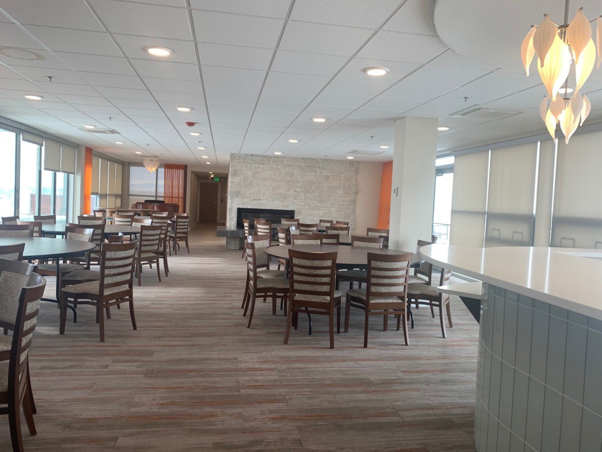 A spacious and modern dining area with several tables and chairs, featuring laminate flooring and ceiling lights.