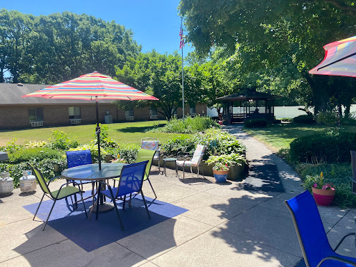 A bright and inviting outdoor patio area with seating, a colorful umbrella, and lush greenery.