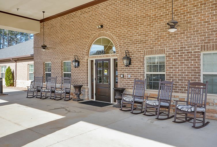 Entrance to a building with a brick facade and outdoor rocking chairs.