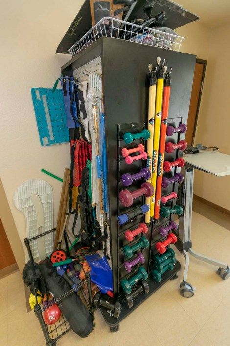 A storage unit filled with various exercise and fitness equipment including dumbbells, therapy bands, and resistance tubes.