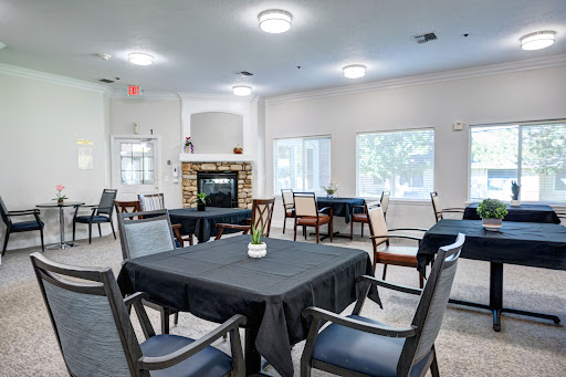 A spacious and bright dining room featuring black tablecloths, elegant furniture, and a cozy fireplace.
