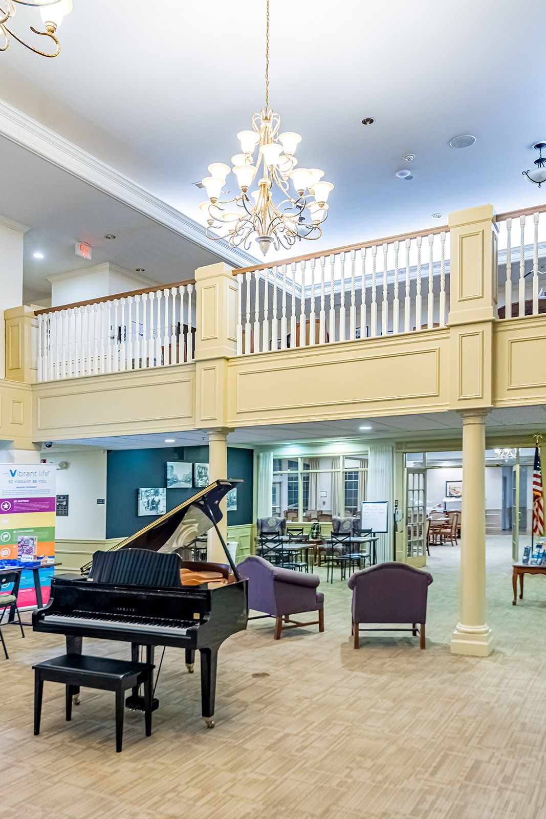 A spacious lobby featuring a grand piano, elegant chandelier, and comfortable seating area.