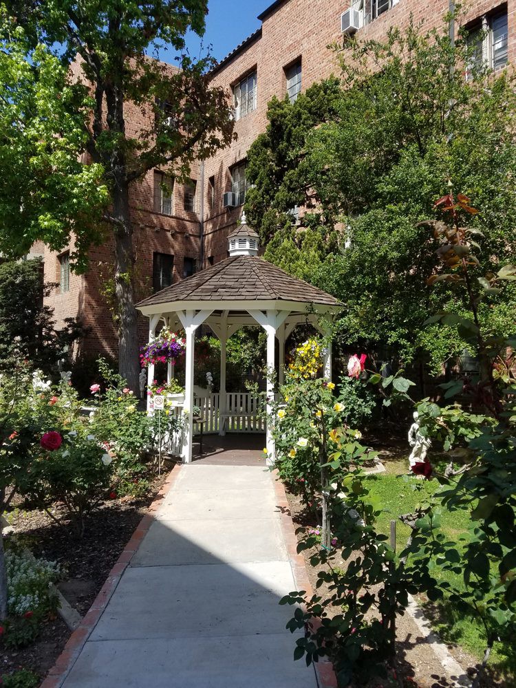 A charming gazebo surrounded by lush greenery and vibrant flowers in a garden setting.