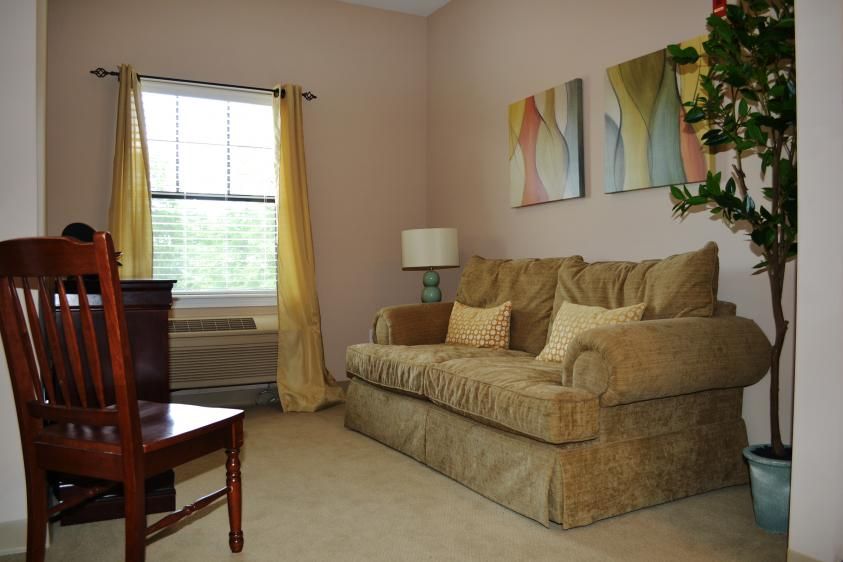 A cozy living room with a beige sofa, colorful artwork, and yellow curtains.