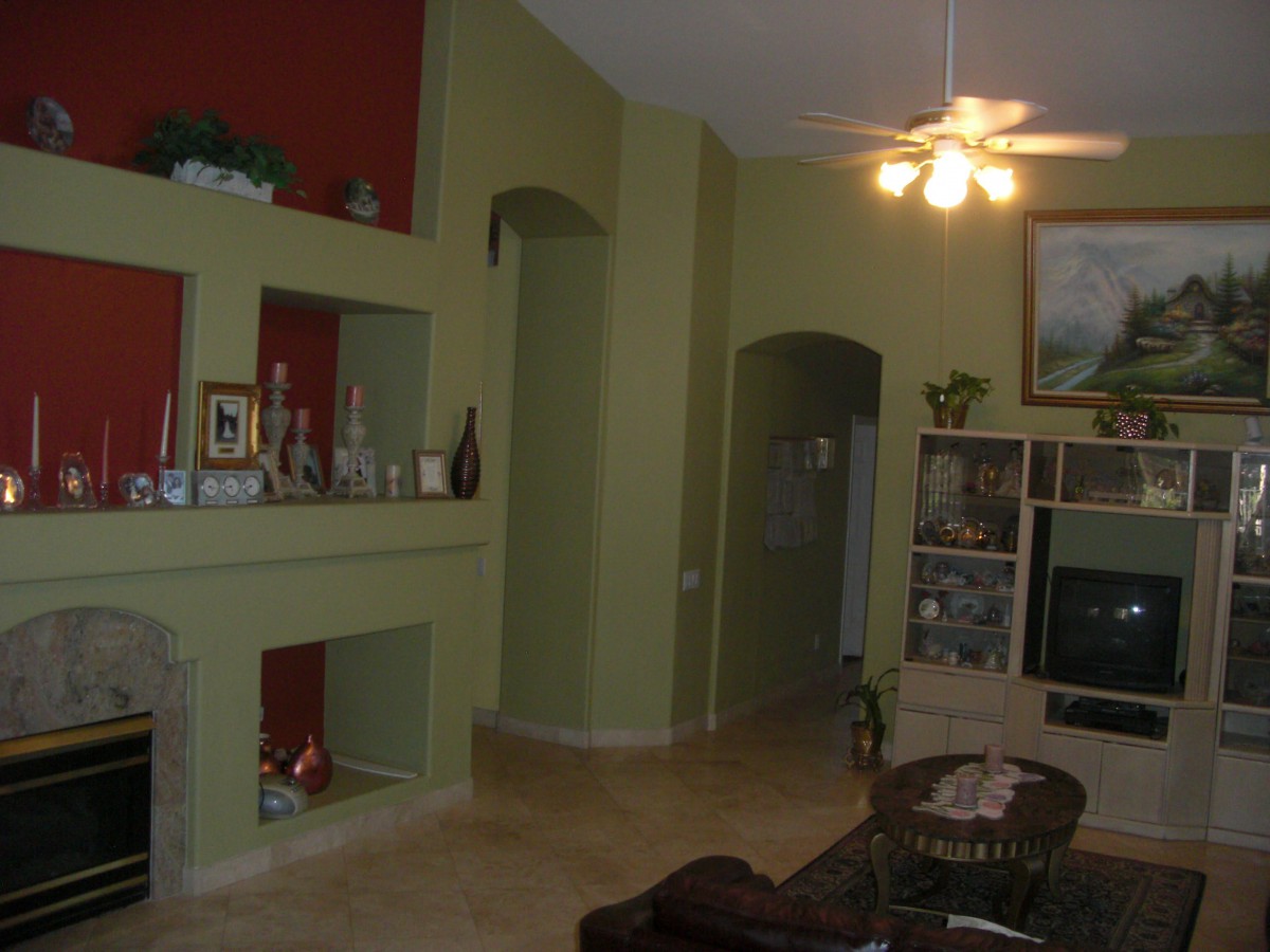 A cozy living room with a unique shelving design and ceiling fan.