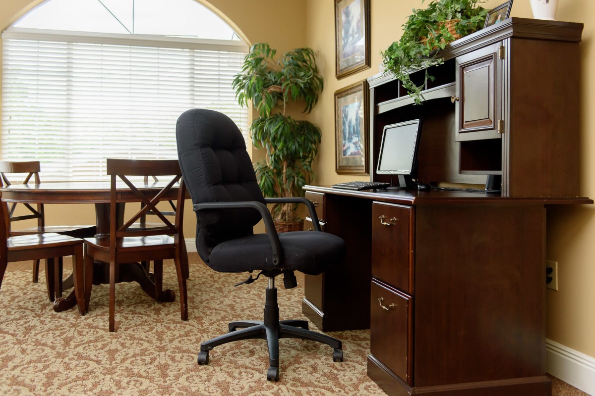 A home office setup with a chair, desk, and computer in a cozy room.