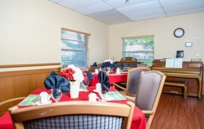 A dining room with elegantly set tables, featuring red tablecloths and folded napkins.
