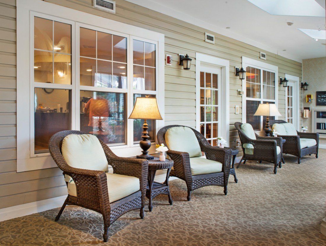 A cozy indoor lounge area with wicker chairs, side tables, and warm lighting.