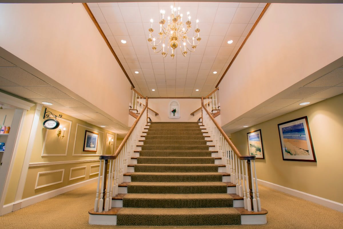 A grand staircase with a chandelier in an elegant interior setting.