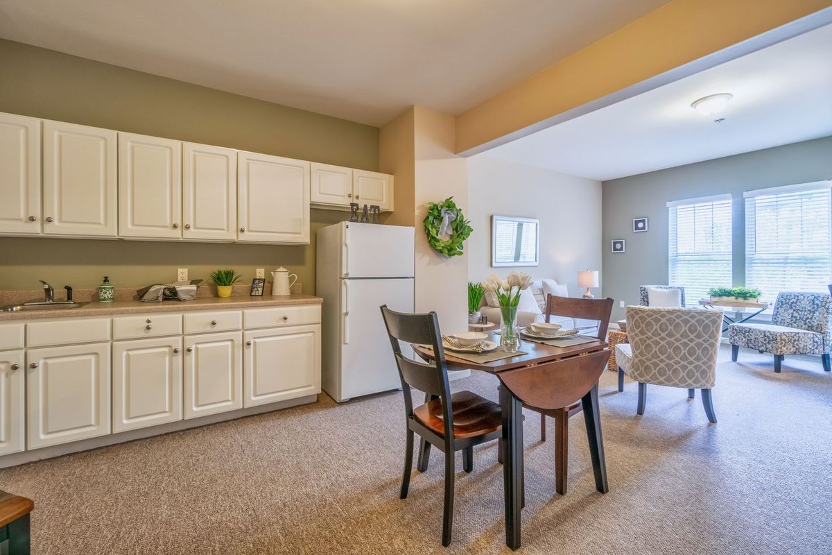 A cozy kitchen and dining area with an adjoining living room, featuring a table set for two.