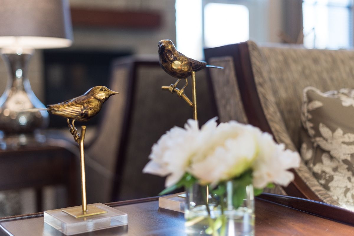 Bronze bird sculptures perched elegantly on a table alongside a white flower arrangement.