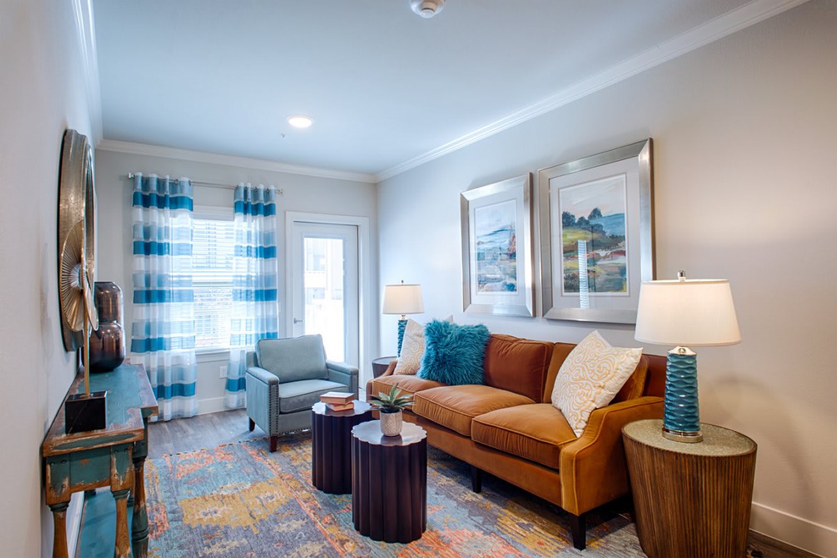 A cozy living room with a stylish sofa, armchair, and two coffee tables, featuring decorative pillows and elegant wall art.