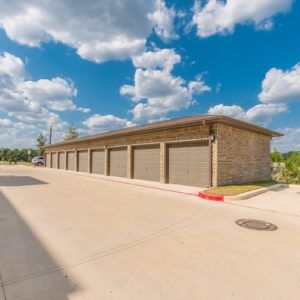 A row of garage storage units under a bright cloudy sky.