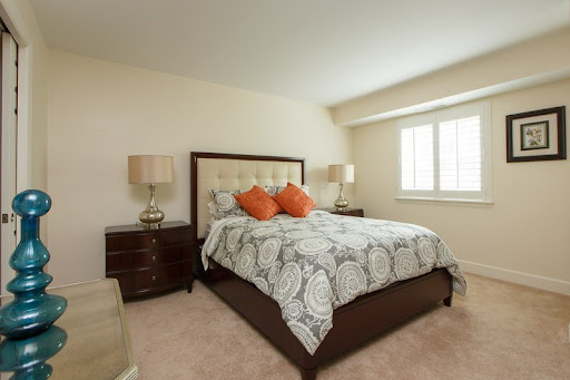 A cozy and elegantly designed bedroom featuring a comfortable bed with decorative pillows, stylish lamps on either side, and ample natural light.