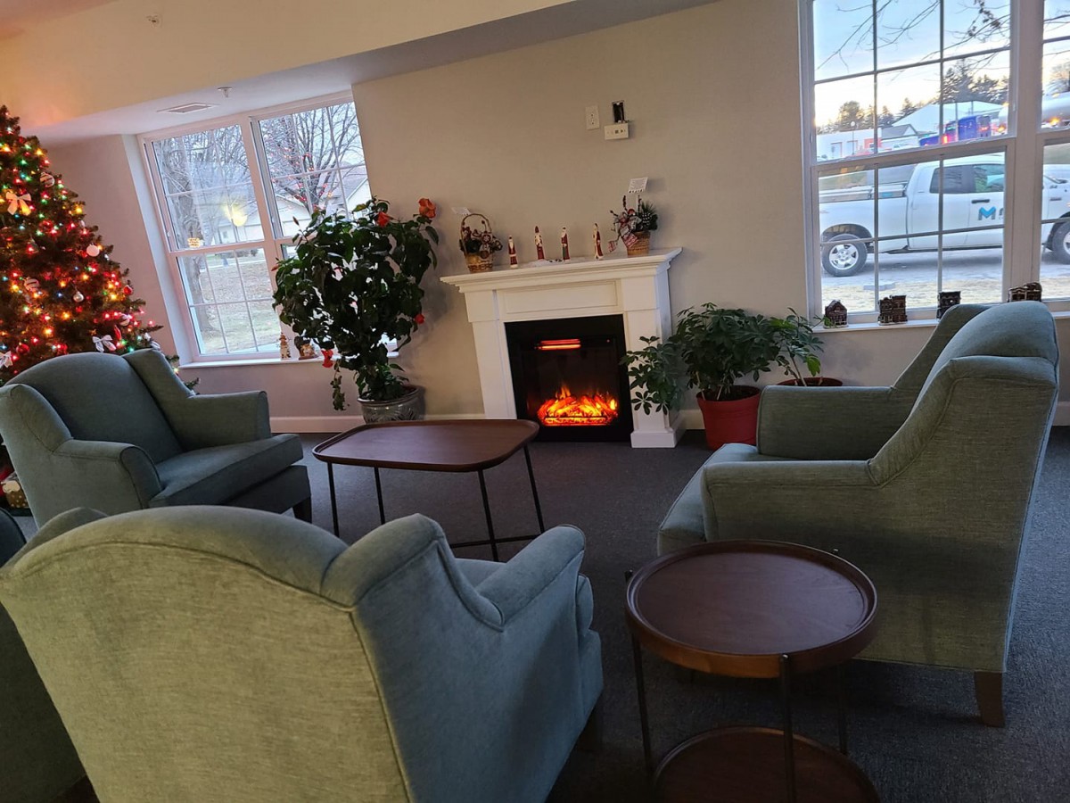 A cozy living room with a fireplace, comfortable seating, and indoor plants.