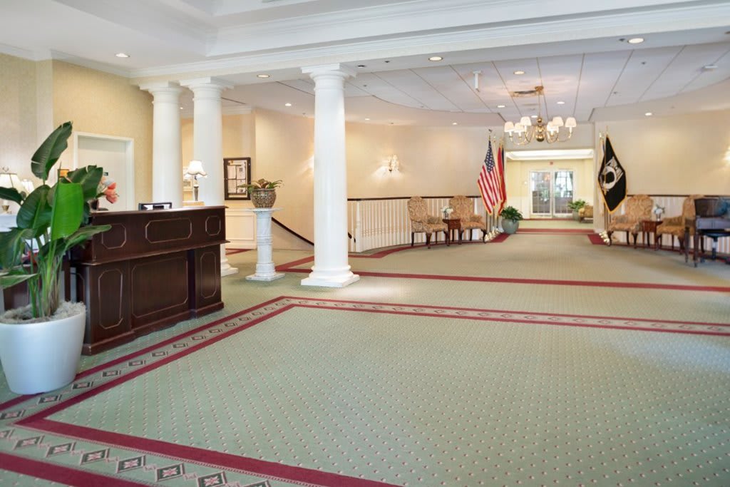 A spacious lobby with a reception desk, columns, and seating area.