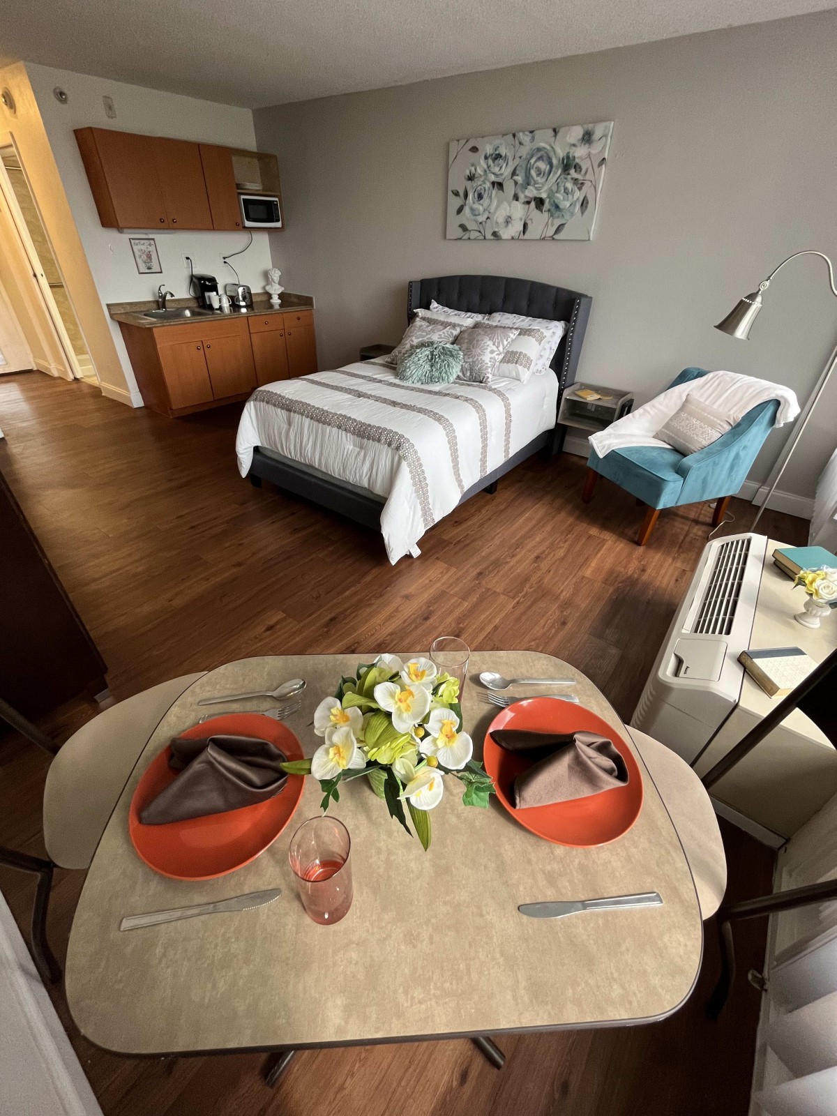 Cozy studio apartment with a neatly arranged bed and a small dining area.