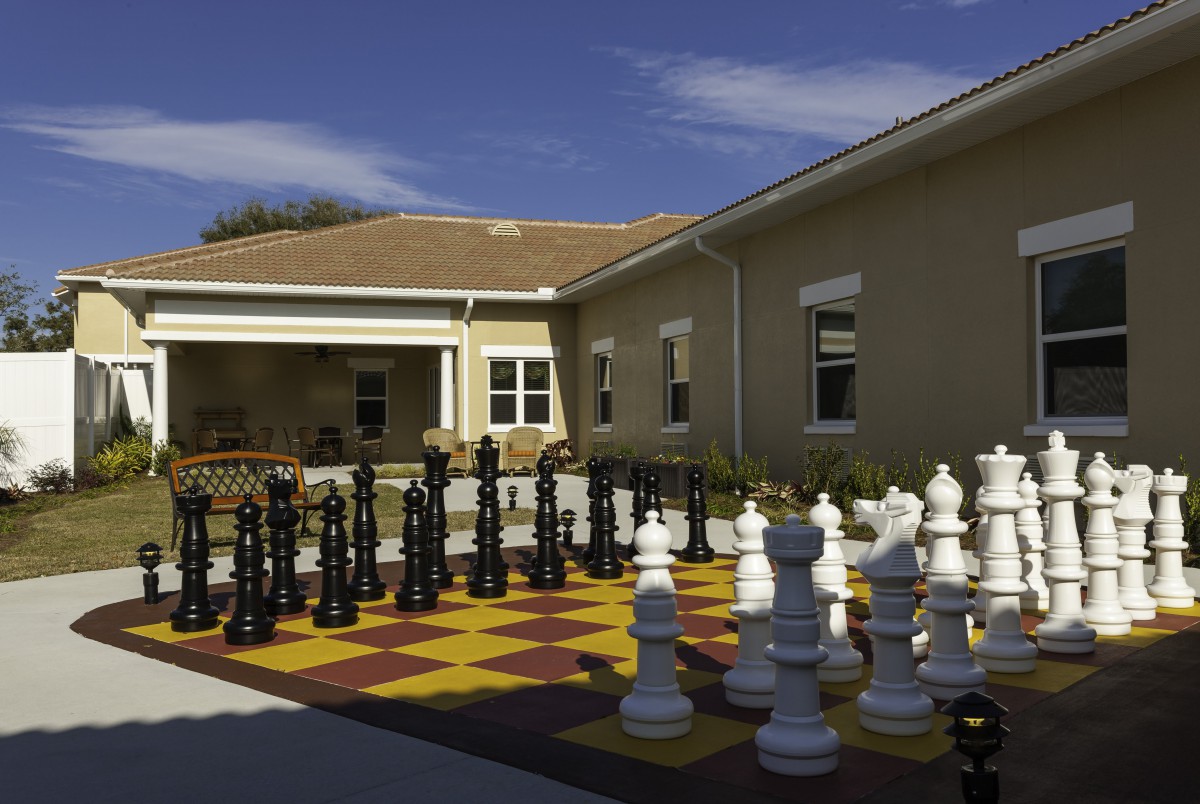 A large outdoor chess set in a sunny courtyard.