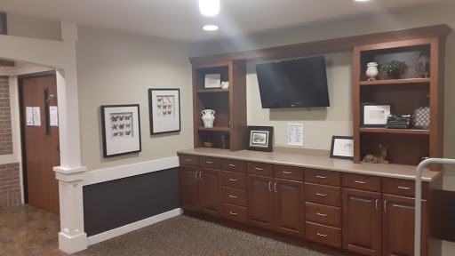 A modern office space featuring wooden cabinets, a television, and framed photographs on the wall.