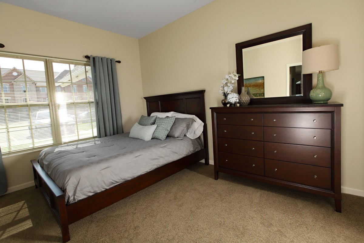 A neatly arranged bedroom with a bed and dresser.