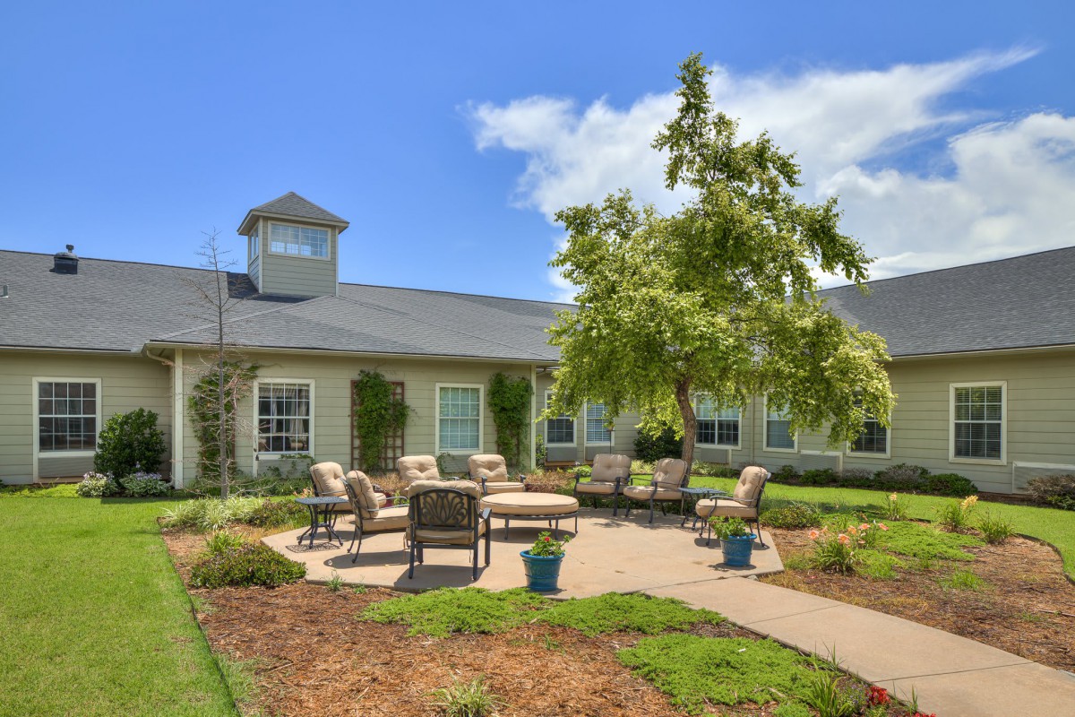 A charming house with a well-maintained garden featuring outdoor seating and a patio on a sunny day.