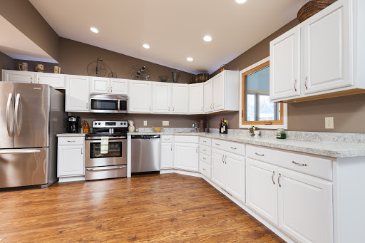 A modern kitchen featuring sleek white cabinets and stainless steel appliances, illuminated by natural light.