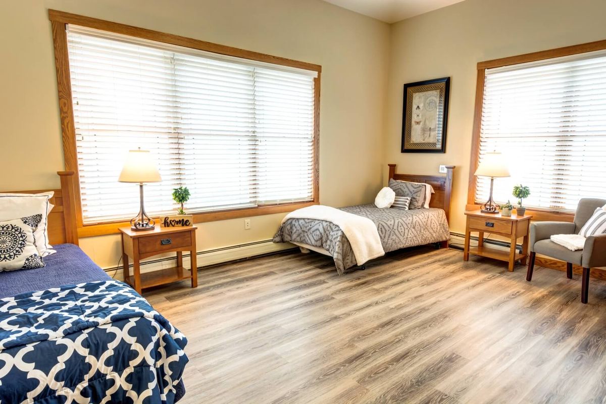 A cozy bedroom with twin beds and natural light streaming through the windows.