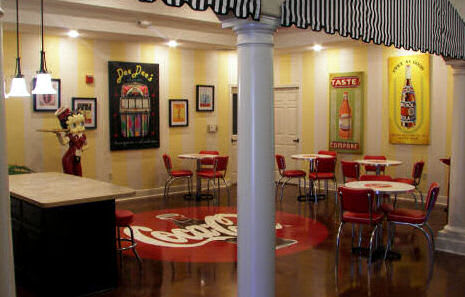 A vintage-style diner interior with Coca-Cola themed decor and red chairs.