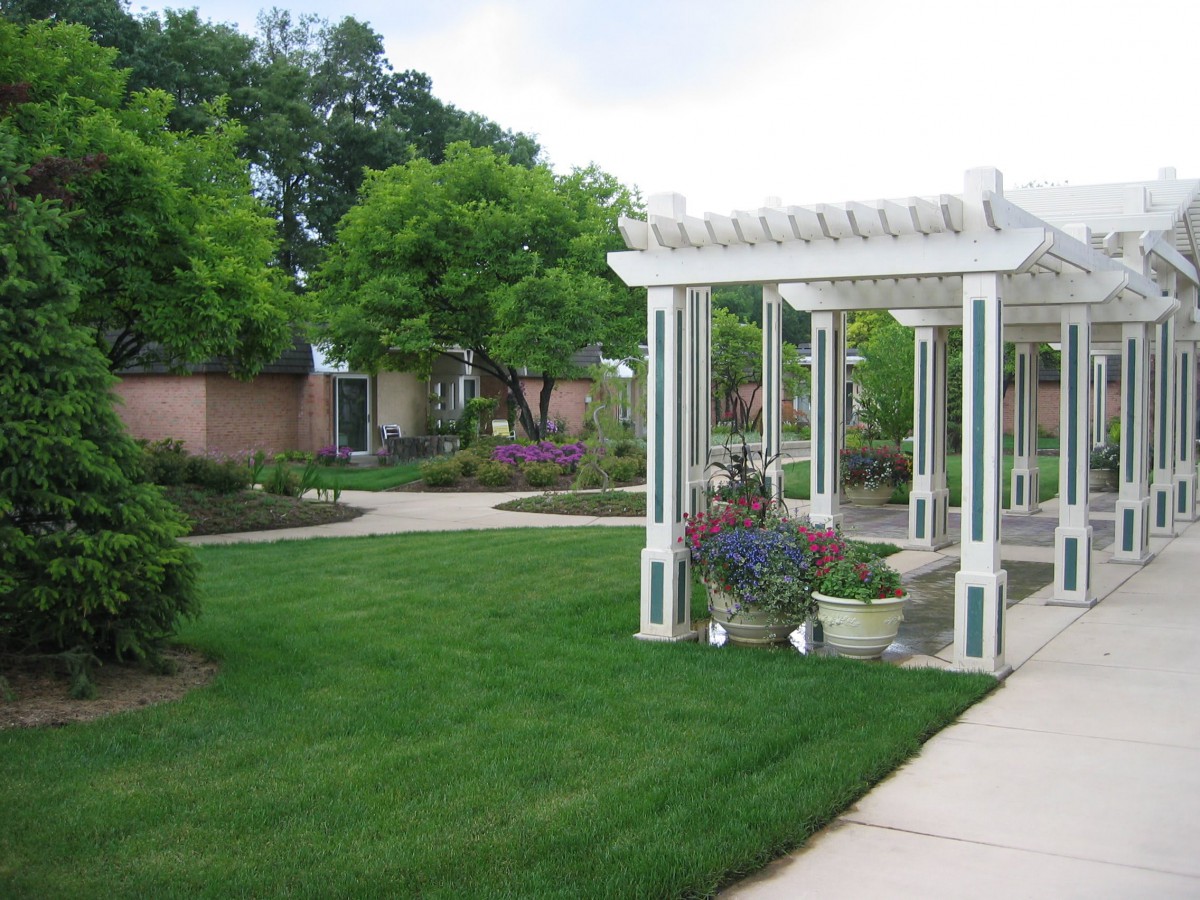 A beautifully landscaped garden featuring a white pergola and lush greenery.