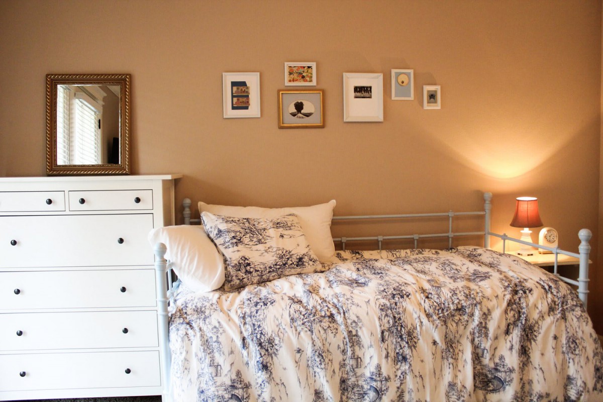 Cozy bedroom with floral bedding and wall art.