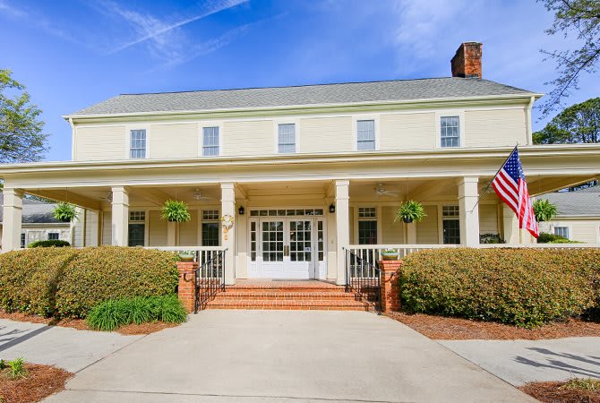 A colonial-style house with a large front porch and paved driveway.
