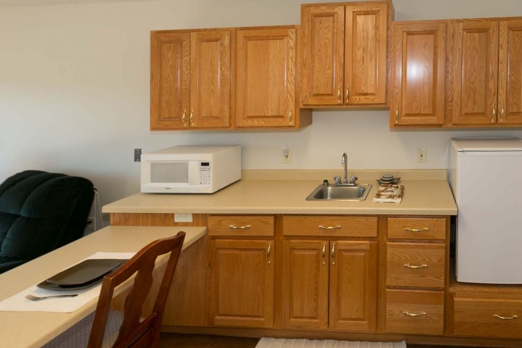 A kitchen with wooden cabinets, a microwave, and a sink on the countertop.