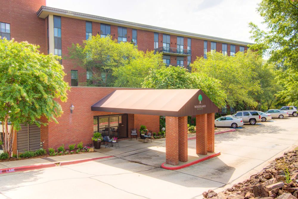 A brick hotel entrance with a covered walkway surrounded by greenery.