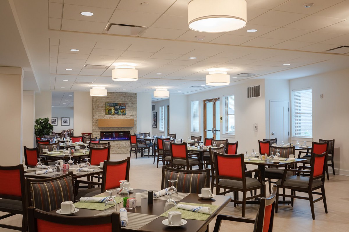 A modern dining room with neatly arranged tables and chairs, featuring elegant lighting fixtures.