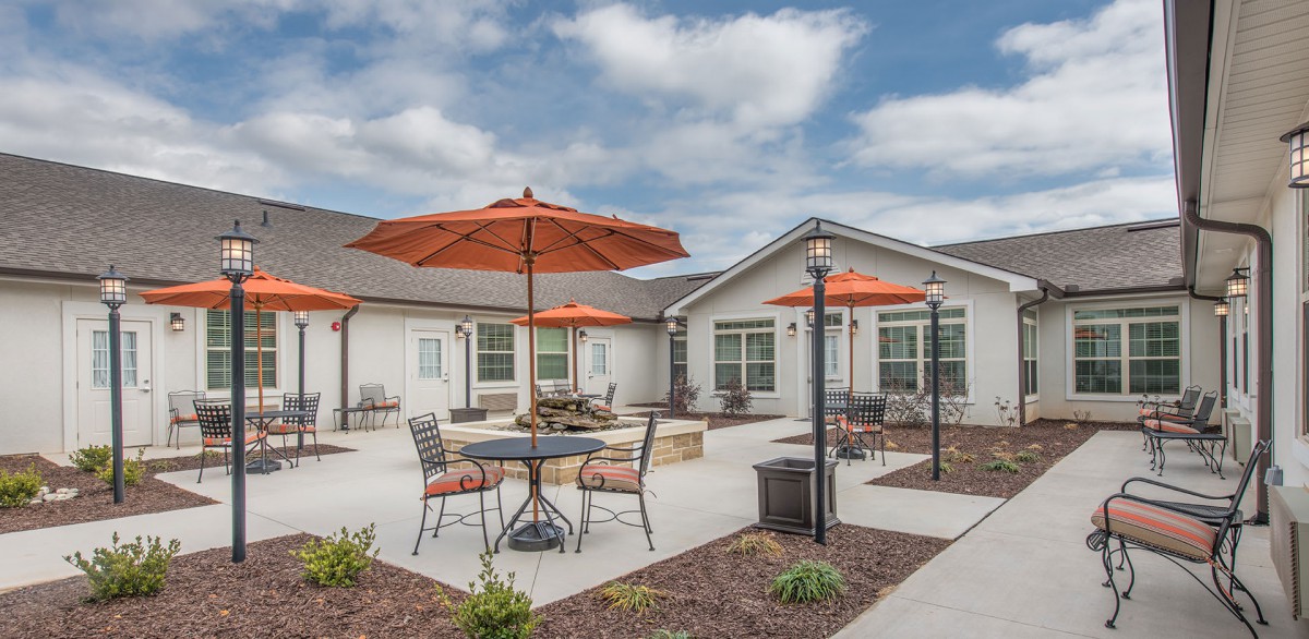 A residential patio area with tables and chairs under orange umbrellas.
