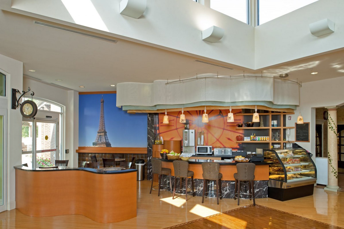A modern kitchen with an open layout featuring a large Eiffel Tower mural, bar seating, and contemporary lighting.