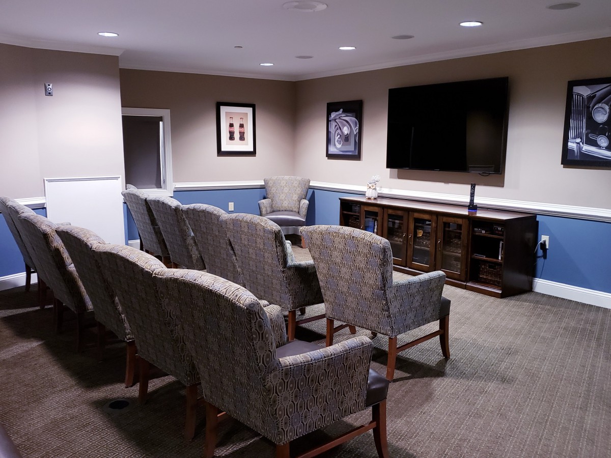 A cozy home theater setup with multiple rows of comfortable chairs facing a large television.