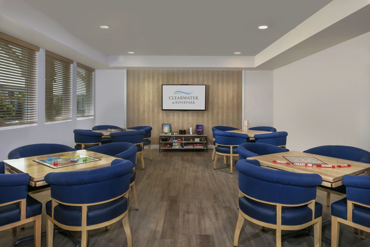 A modern lounge with blue chairs and a television on a wooden accent wall.