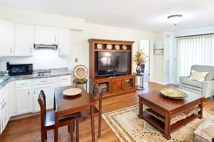 A cozy living room with a dining area, featuring wood furniture and a large television.