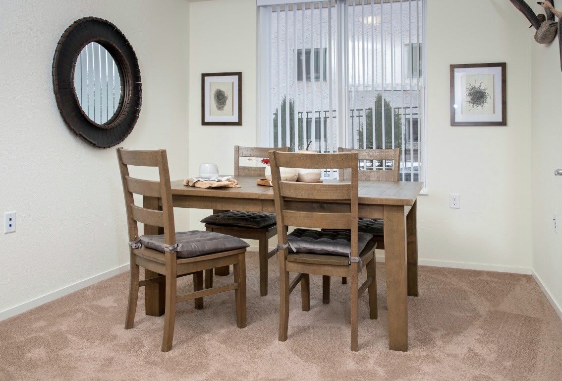 A cozy dining room with a wooden table and chairs, accented by decorative elements like wall art and a mirror.