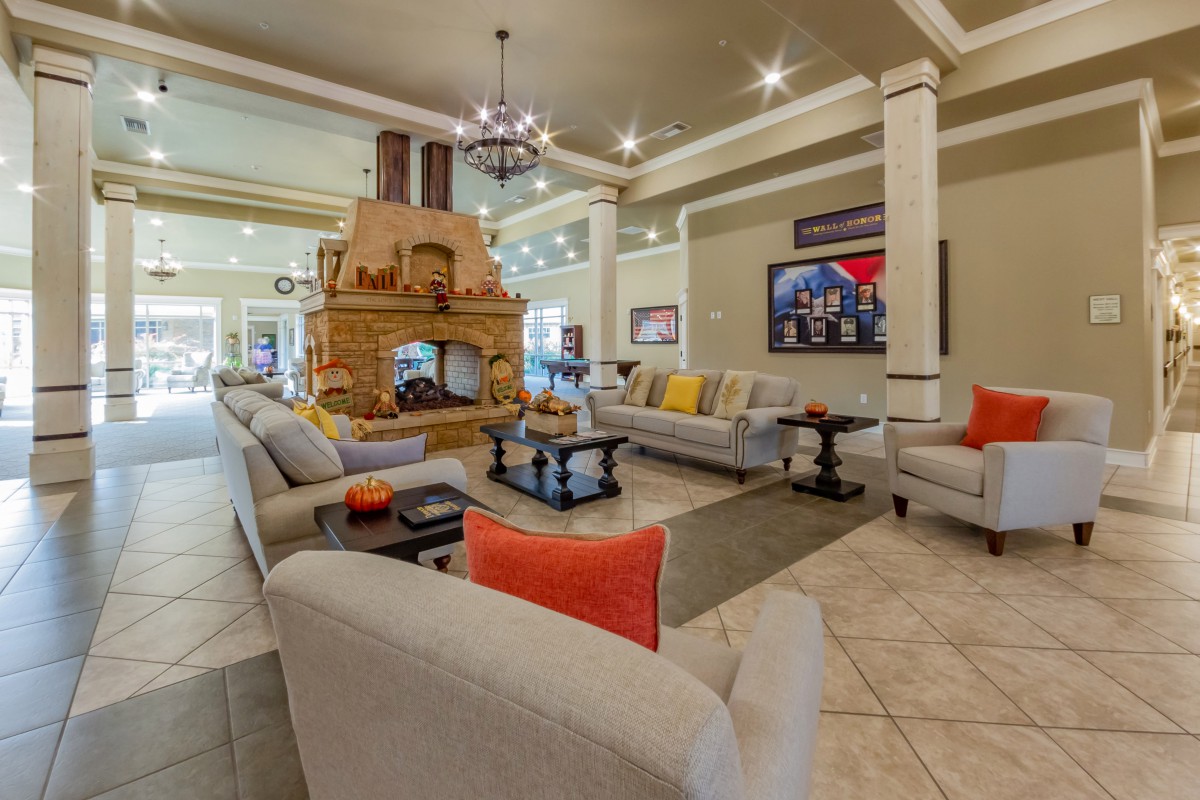 A spacious living room with modern decor, featuring a central fireplace, comfortable sofas, and elegant lighting.