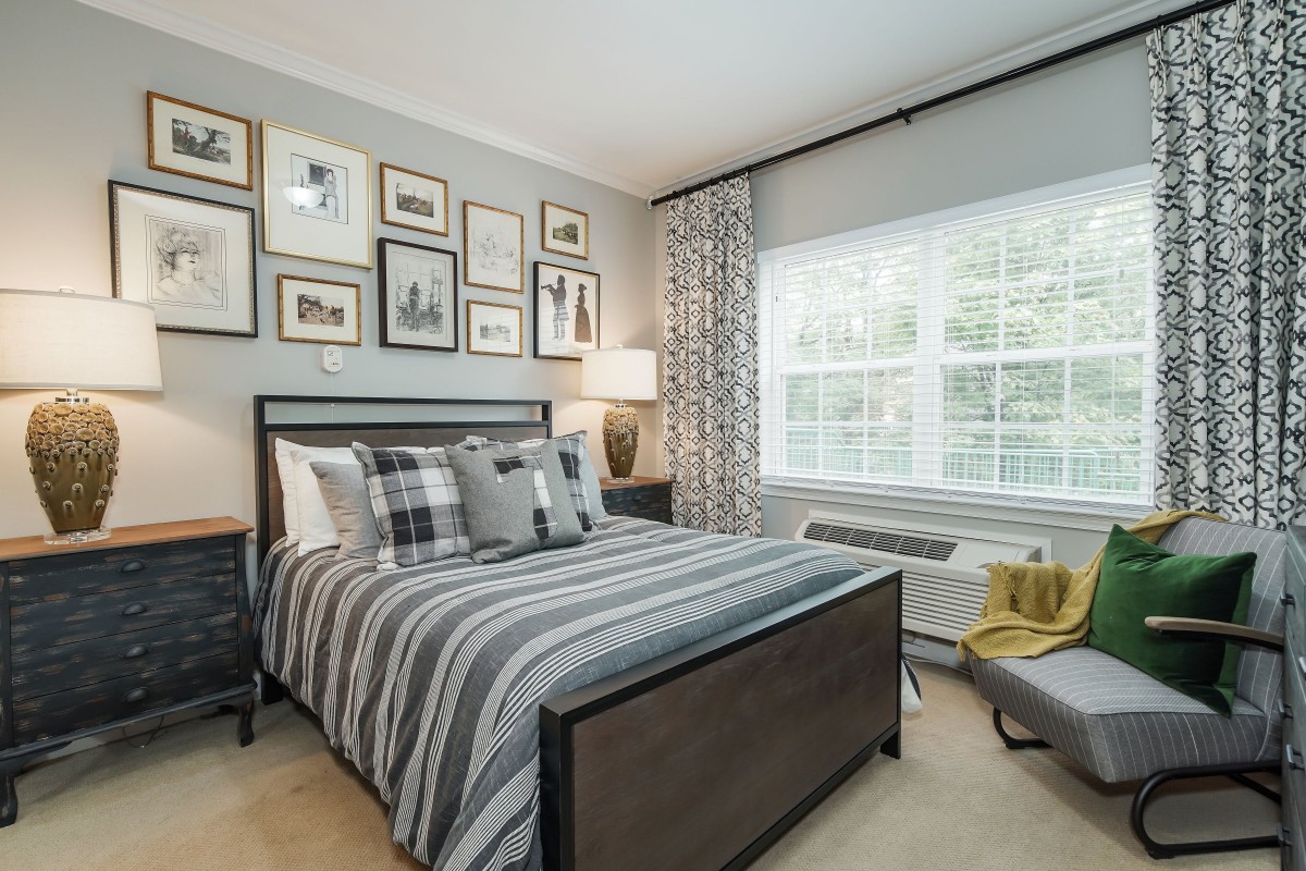 A stylishly decorated bedroom with striped bedding and a gallery wall of framed pictures.