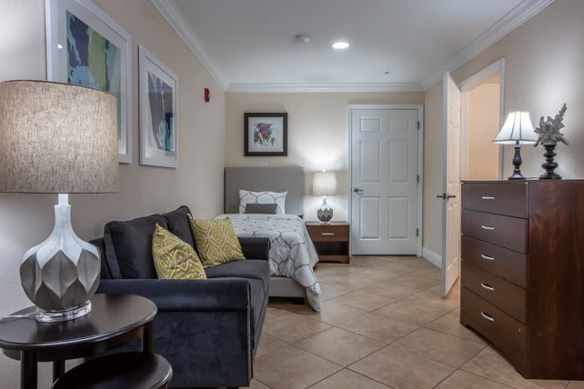 Cozy living space with a sofa and bed, accented by warm lighting and decor.