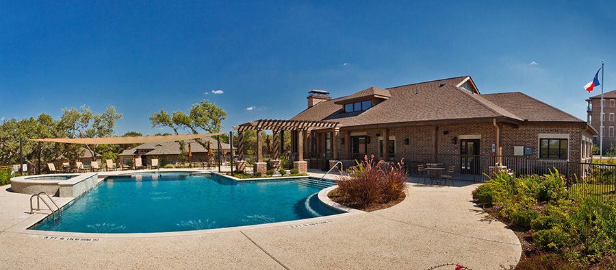 A luxurious house with a swimming pool and patio area under a clear blue sky.