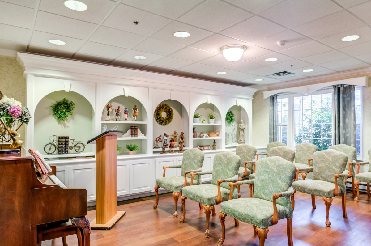 A small chapel with rows of chairs facing a podium, surrounded by decorated shelves.